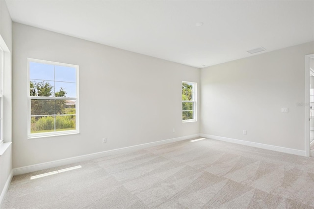 spare room featuring light colored carpet and baseboards