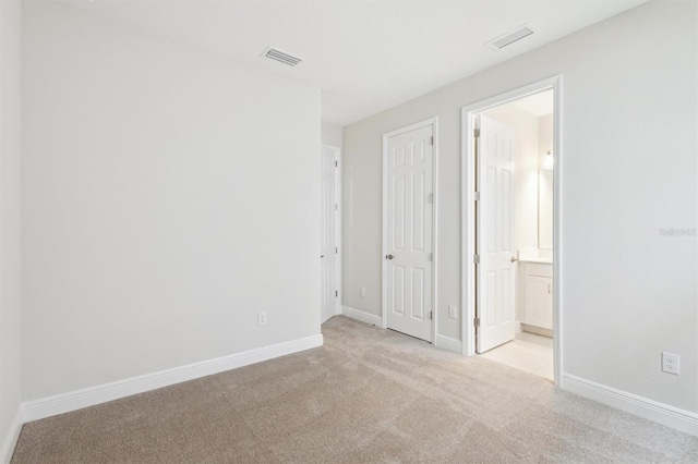 unfurnished bedroom with carpet floors, baseboards, and connected bathroom