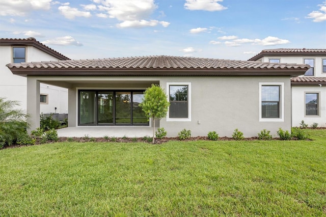 rear view of house featuring stucco siding, a lawn, and a patio