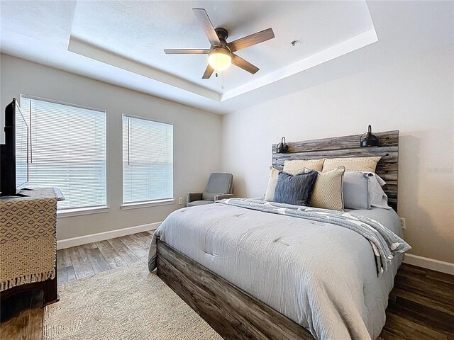 18001 Richmond Place Dr Unit 330, Tampa, FL 33647 - bedroom featuring a tray ceiling, baseboards, wood finished floors, and a ceiling fan