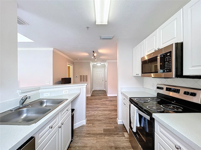 18001 Richmond Place Dr Unit 330, Tampa, FL 33647 - kitchen with appliances with stainless steel finishes, a sink, dark wood-style flooring, backsplash, and white cabinetry