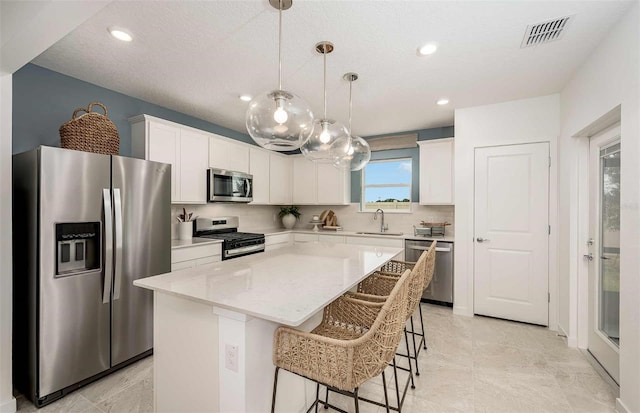 8303 SW 54th Loop, Ocala, FL 34481 - kitchen featuring stainless steel appliances, a sink, a kitchen island, a kitchen bar, and white cabinetry