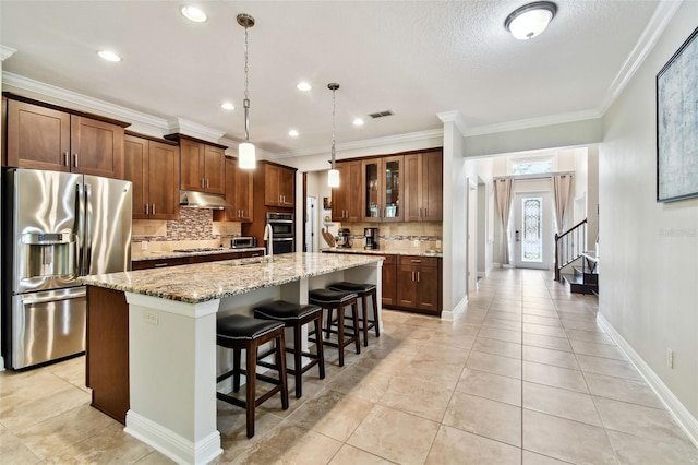 11624 Calf Path Dr, Tampa, FL 33626 - kitchen featuring stainless steel appliances, under cabinet range hood, tasteful backsplash, a kitchen bar, and a center island with sink