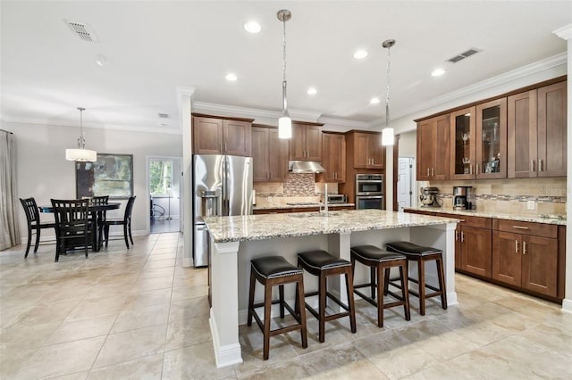 11624 Calf Path Dr, Tampa, FL 33626 - kitchen with stainless steel appliances, under cabinet range hood, decorative backsplash, an island with sink, and a kitchen breakfast bar
