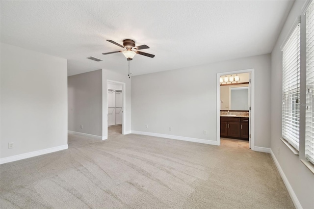 11624 Calf Path Dr, Tampa, FL 33626 - unfurnished bedroom with light colored carpet, a walk in closet, multiple windows, and a textured ceiling