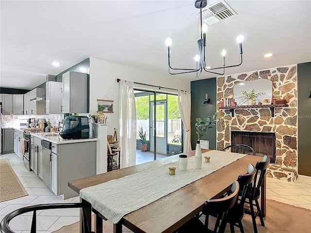 dining space with a stone fireplace, light tile patterned floors, a chandelier, and recessed lighting