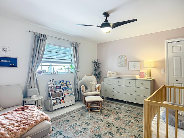 bedroom featuring a crib, a ceiling fan, and light tile patterned floors