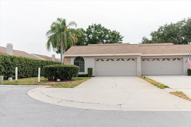 view of front of house with stucco siding, concrete driveway, and a shingled roof