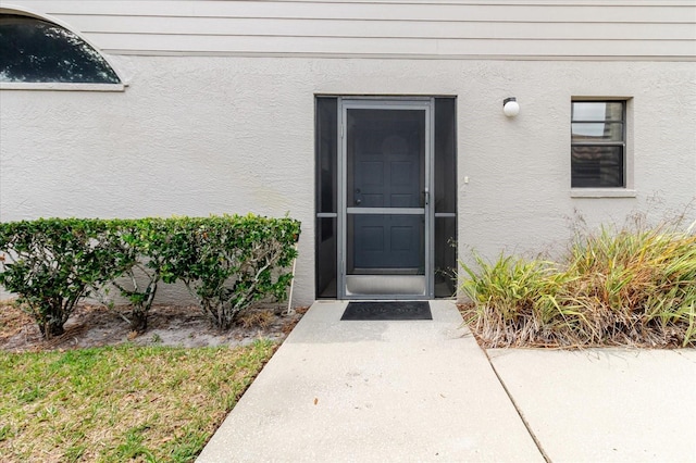 doorway to property featuring stucco siding
