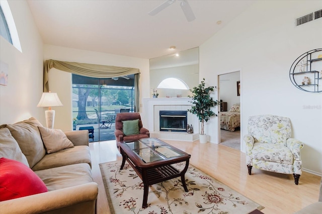 living room featuring wood finished floors, a tiled fireplace, and ceiling fan