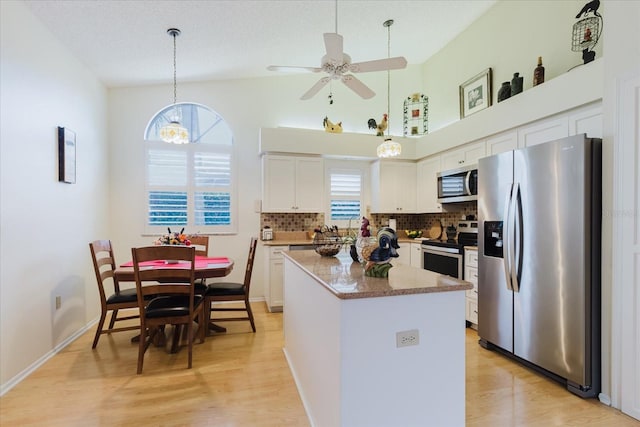 kitchen featuring appliances with stainless steel finishes, a kitchen island, light wood-style flooring, and white cabinets