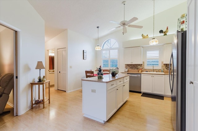 kitchen featuring appliances with stainless steel finishes, light wood-style flooring, ceiling fan, white cabinets, and a kitchen island