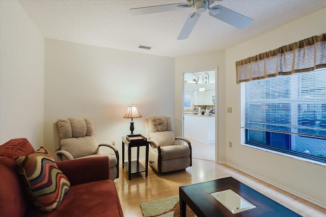 sitting room with a ceiling fan, light wood-style floors, and a textured ceiling