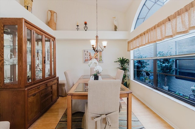 dining space featuring light wood-style flooring, a chandelier, and a towering ceiling