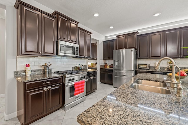 3212 Calvano Dr, Land O Lakes, FL 34639 - kitchen featuring appliances with stainless steel finishes, a sink, dark stone countertops, decorative backsplash, and dark brown cabinetry