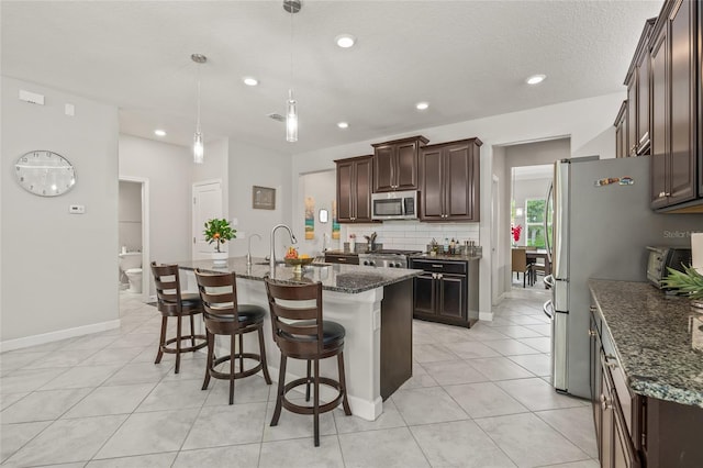 3212 Calvano Dr, Land O Lakes, FL 34639 - kitchen with appliances with stainless steel finishes, a breakfast bar, backsplash, dark brown cabinets, and dark stone counters