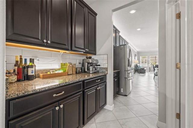 3212 Calvano Dr, Land O Lakes, FL 34639 - kitchen with stainless steel fridge, decorative backsplash, light tile patterned floors, stone countertops, and dark brown cabinets