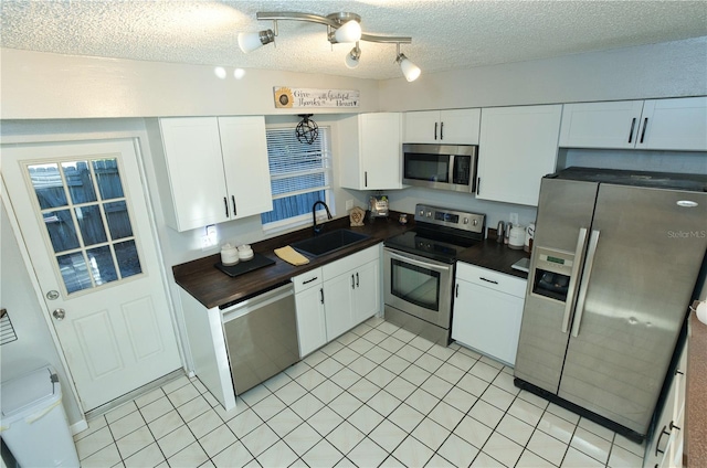 300 6th St N Unit E3, Safety Harbor, FL 34695 - kitchen featuring appliances with stainless steel finishes, a sink, a textured ceiling, white cabinetry, and light tile patterned flooring