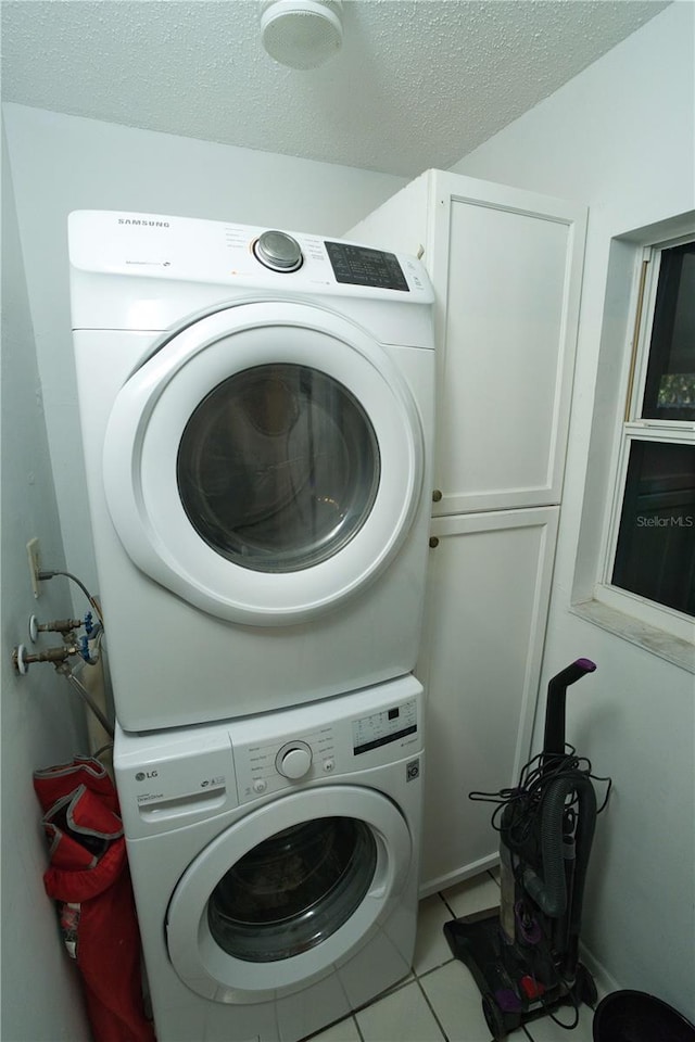 300 6th St N Unit E3, Safety Harbor, FL 34695 - laundry area with stacked washer / dryer, cabinet space, a textured ceiling, and light tile patterned floors