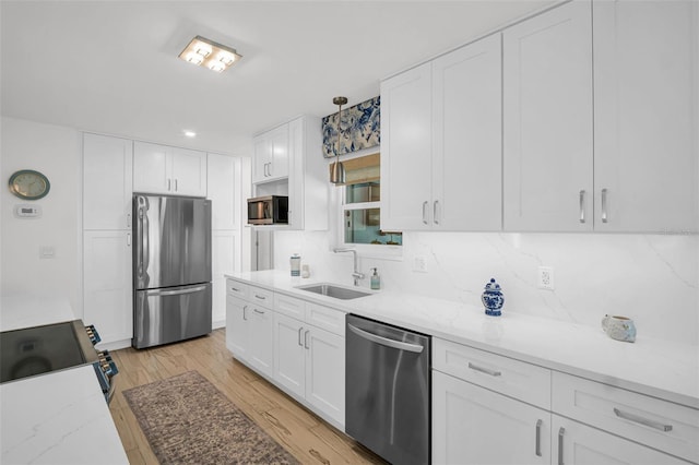 1769 Brookside Blvd, Largo, FL 33770 - kitchen featuring stainless steel appliances, a sink, white cabinets, light wood-type flooring, and tasteful backsplash