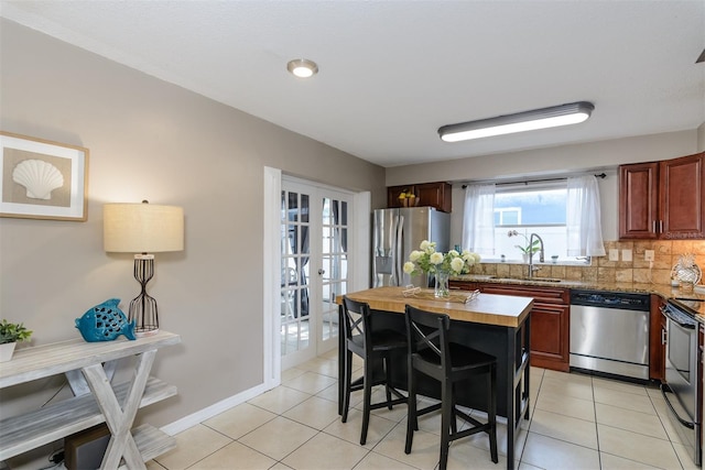 2012 Scotland Dr, Clearwater, FL 33763 - kitchen with appliances with stainless steel finishes, a sink, butcher block countertops, decorative backsplash, and french doors