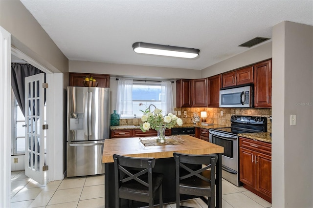 2012 Scotland Dr, Clearwater, FL 33763 - kitchen with stainless steel appliances, wooden counters, light tile patterned flooring, and decorative backsplash