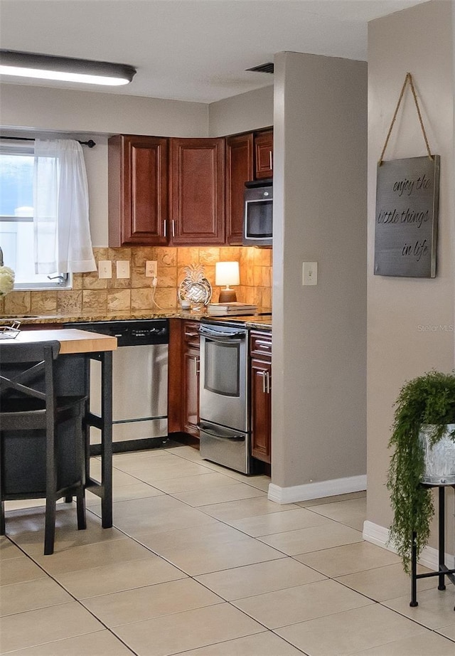 2012 Scotland Dr, Clearwater, FL 33763 - kitchen featuring appliances with stainless steel finishes, tasteful backsplash, light tile patterned flooring, and light countertops