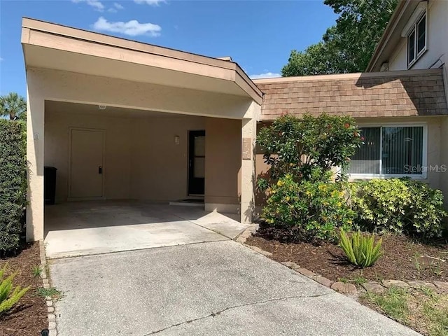 2720 Sand Hollow Ct Unit 156A, Clearwater, FL 33761 - entrance to property featuring stucco siding, concrete driveway, a shingled roof, and a carport