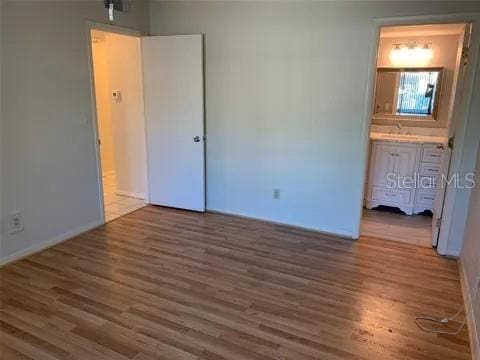 2720 Sand Hollow Ct Unit 156A, Clearwater, FL 33761 - unfurnished bedroom with wood finished floors, a sink, baseboards, and ensuite bath