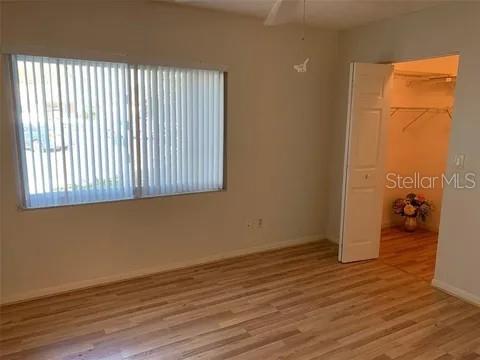 2720 Sand Hollow Ct Unit 156A, Clearwater, FL 33761 - unfurnished bedroom featuring wood finished floors, a closet, a walk in closet, and baseboards