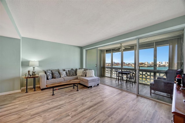 31 Island Way Unit 1403, Clearwater Beach, FL 33767 - living room with a textured ceiling, wood finished floors, baseboards, and a water view