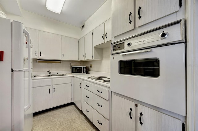 31 Island Way Unit 1403, Clearwater Beach, FL 33767 - kitchen featuring white appliances, a sink, light countertops, and decorative backsplash