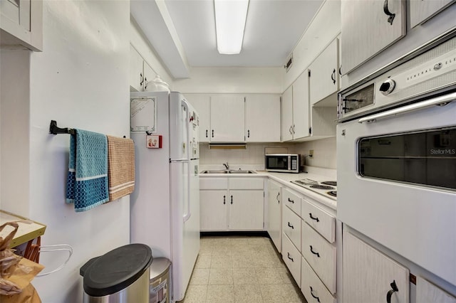 31 Island Way Unit 1403, Clearwater Beach, FL 33767 - kitchen featuring white appliances, light countertops, a sink, and white cabinets