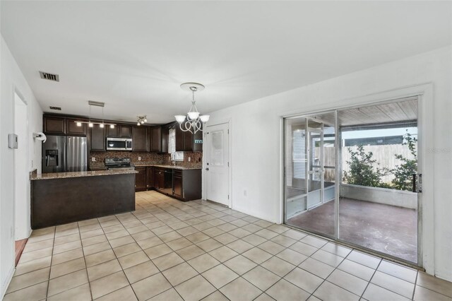 503 Holt Cir, Winter Haven, FL 33880 - kitchen featuring stainless steel appliances, dark brown cabinetry, tasteful backsplash, a chandelier, and a peninsula