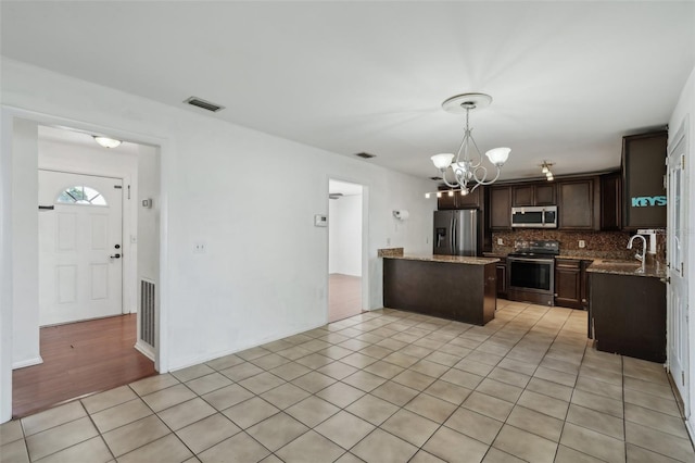 503 Holt Cir, Winter Haven, FL 33880 - kitchen with appliances with stainless steel finishes, a chandelier, dark brown cabinets, a sink, and decorative backsplash