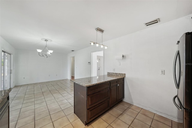 503 Holt Cir, Winter Haven, FL 33880 - kitchen with freestanding refrigerator, a chandelier, a peninsula, light tile patterned floors, and light stone countertops
