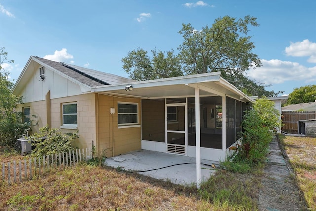 503 Holt Cir, Winter Haven, FL 33880 - back of property featuring a sunroom, solar panels, fence, a patio area, and a shingled roof