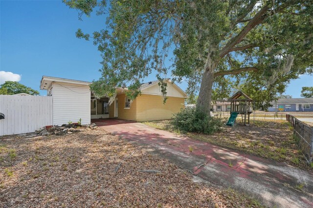 503 Holt Cir, Winter Haven, FL 33880 - view of yard featuring a playground, fence, concrete driveway, and an attached carport