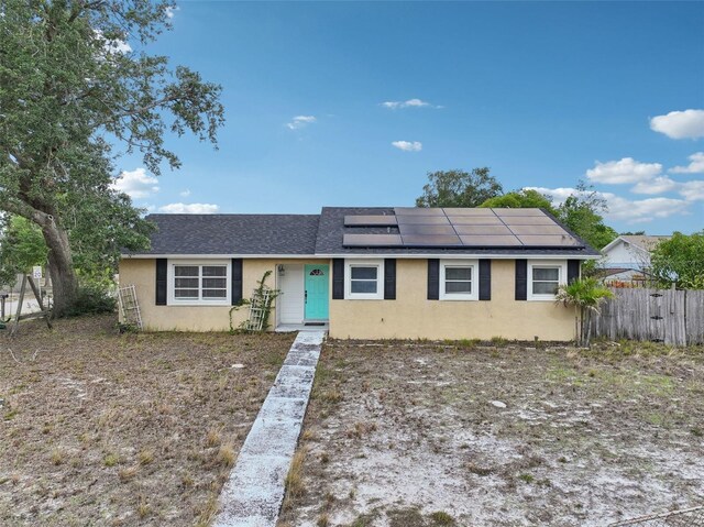 503 Holt Cir, Winter Haven, FL 33880 - ranch-style house with stucco siding, solar panels, fence, and a shingled roof
