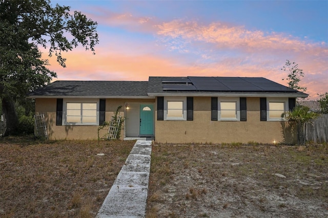 503 Holt Cir, Winter Haven, FL 33880 - view of front of property with stucco siding, solar panels, a shingled roof, and fence
