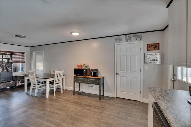 dining area with crown molding, wood finished floors, and baseboards