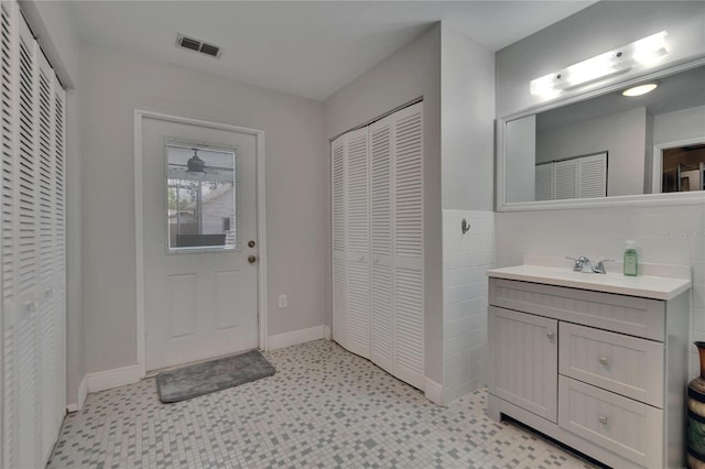 bathroom with a closet, tile patterned floors, vanity, and baseboards