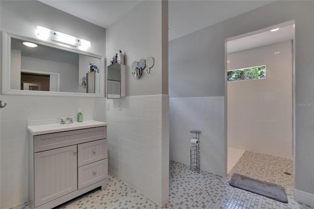 bathroom with walk in shower, vanity, and tile walls