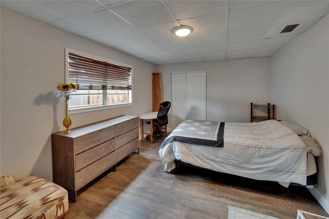 bedroom with light wood-style floors, a closet, and a drop ceiling