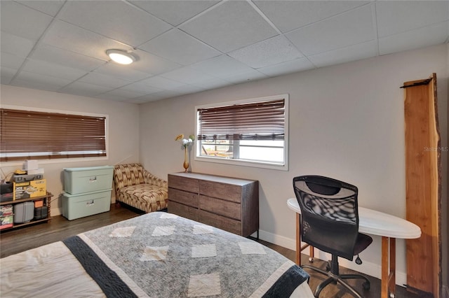 bedroom featuring baseboards, dark wood finished floors, and a drop ceiling
