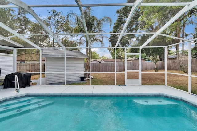 view of swimming pool with a storage unit, an outbuilding, a fenced backyard, and glass enclosure