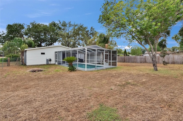 rear view of property with an outdoor fire pit and glass enclosure