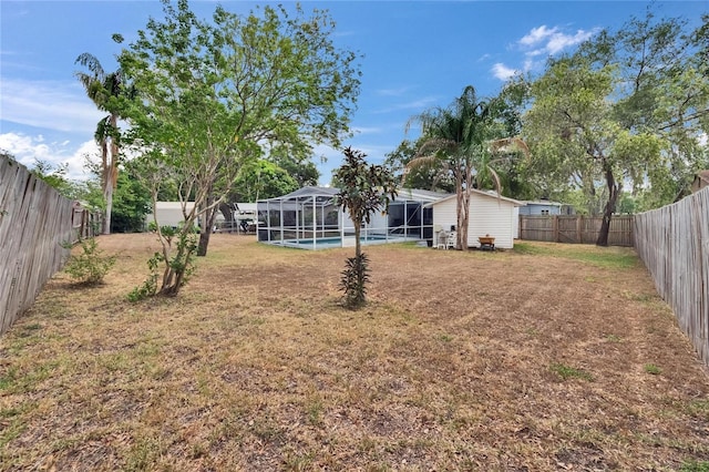 view of yard featuring glass enclosure, an outdoor structure, and a storage shed