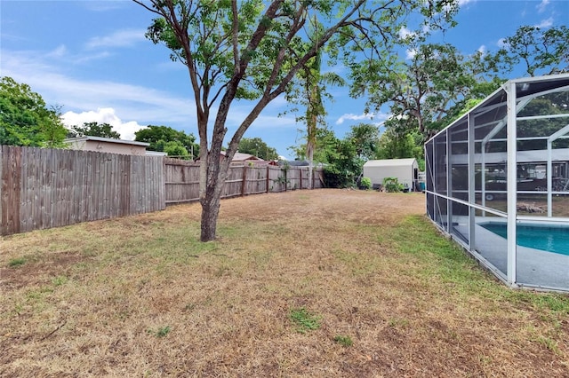 view of yard featuring glass enclosure, a shed, and an outdoor structure