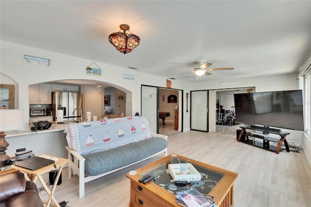 6530 Manila Palm Way, Apollo Beach, FL 33572 - living room featuring arched walkways, a ceiling fan, light wood-style floors, and a chandelier